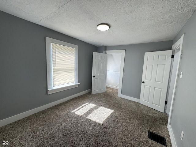 unfurnished bedroom with visible vents, carpet flooring, a textured ceiling, and baseboards