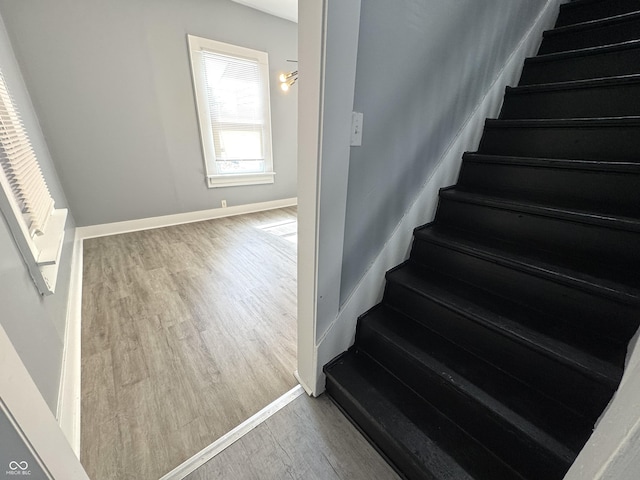 stairway with wood finished floors and baseboards