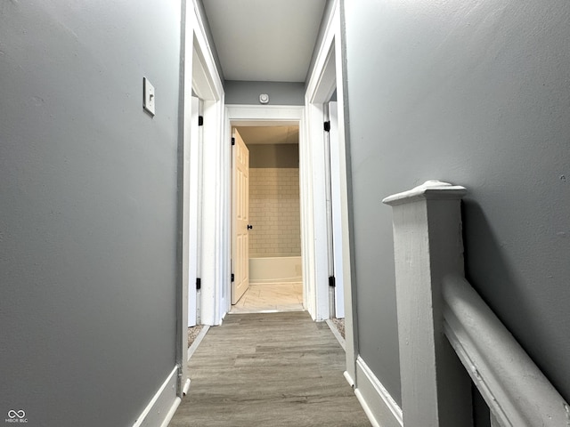 corridor featuring baseboards and wood finished floors