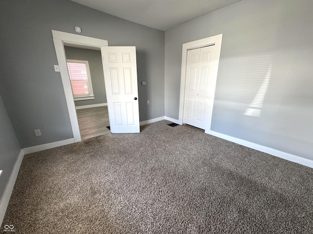 unfurnished bedroom featuring lofted ceiling, carpet flooring, baseboards, and a closet