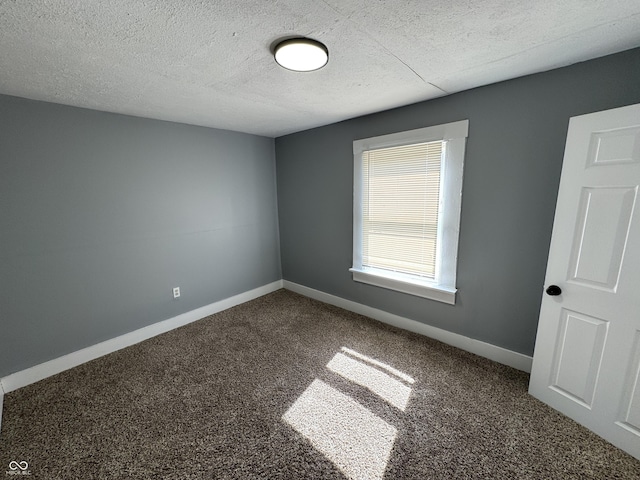 empty room featuring baseboards, carpet floors, and a textured ceiling