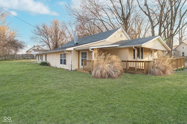 rear view of property featuring a lawn and fence