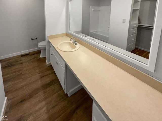 full bathroom featuring vanity, wood finished floors, baseboards,  shower combination, and toilet