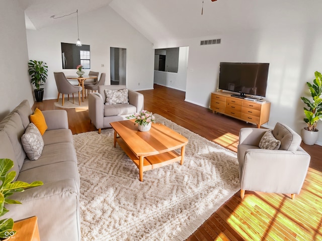 living room with vaulted ceiling, wood finished floors, visible vents, and ceiling fan