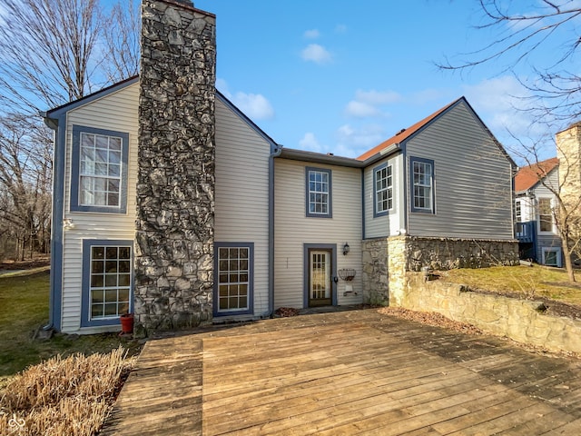 back of property featuring a chimney, stone siding, and a wooden deck