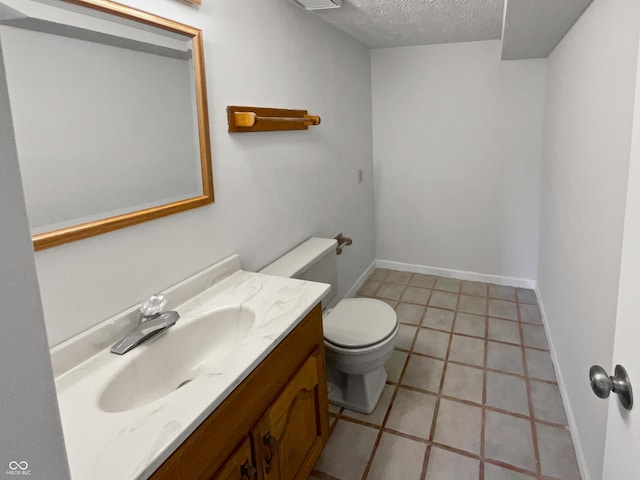 half bathroom featuring toilet, a textured ceiling, vanity, and baseboards