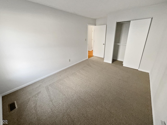 unfurnished bedroom featuring a closet, visible vents, baseboards, and carpet