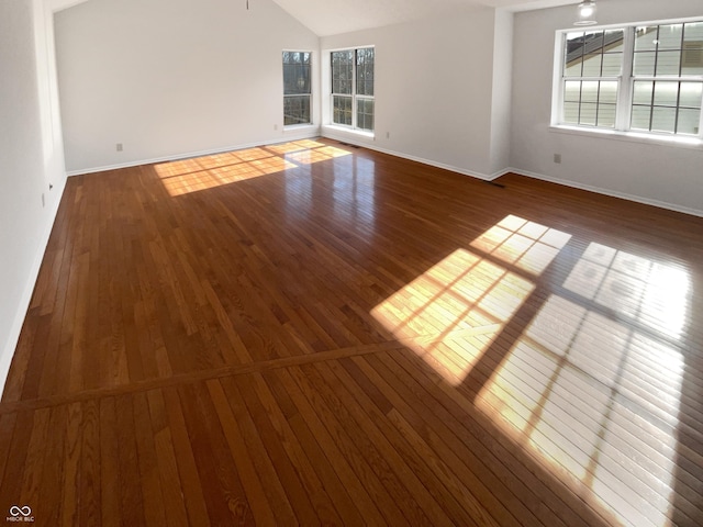 unfurnished room featuring vaulted ceiling, baseboards, and hardwood / wood-style flooring