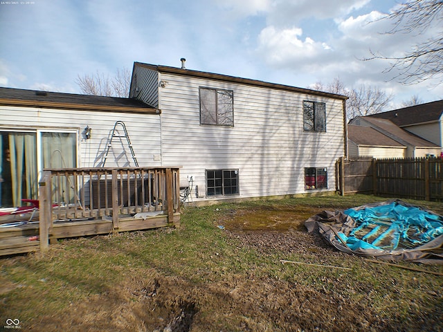 rear view of house with a wooden deck, a lawn, and fence