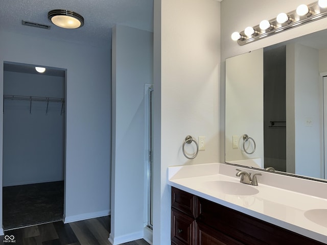 full bath with wood finished floors, visible vents, a sink, a spacious closet, and a textured ceiling