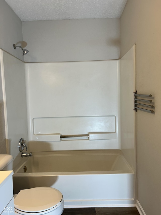 bathroom with a textured ceiling, toilet, vanity, and shower / bathtub combination