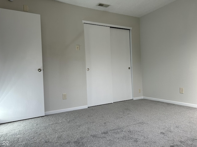 unfurnished bedroom with visible vents, baseboards, carpet, and a closet