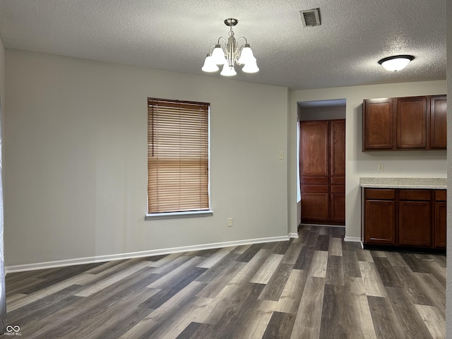 kitchen featuring dark wood-type flooring, baseboards, pendant lighting, light countertops, and an inviting chandelier