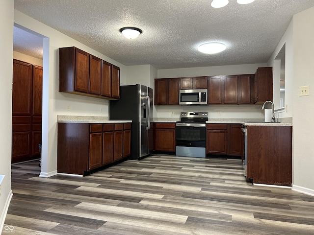 kitchen with a sink, light countertops, wood finished floors, and stainless steel appliances