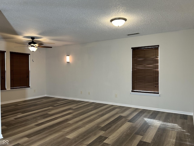 spare room featuring dark wood-style floors, a ceiling fan, and baseboards