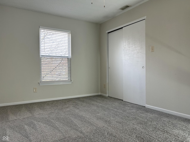 unfurnished bedroom with visible vents, baseboards, a closet, and carpet floors