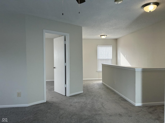 carpeted empty room with baseboards, a textured ceiling, and ceiling fan