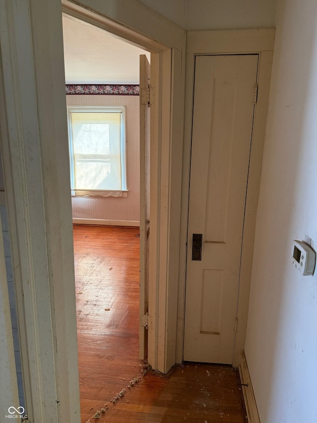 corridor with baseboards and wood-type flooring