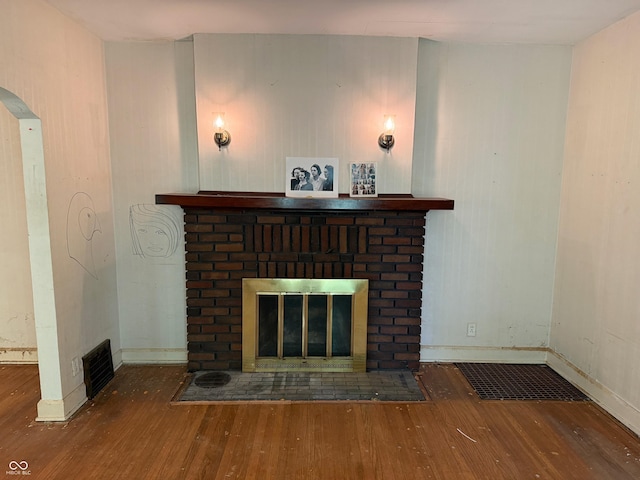 details with wood finished floors, visible vents, baseboards, arched walkways, and a brick fireplace