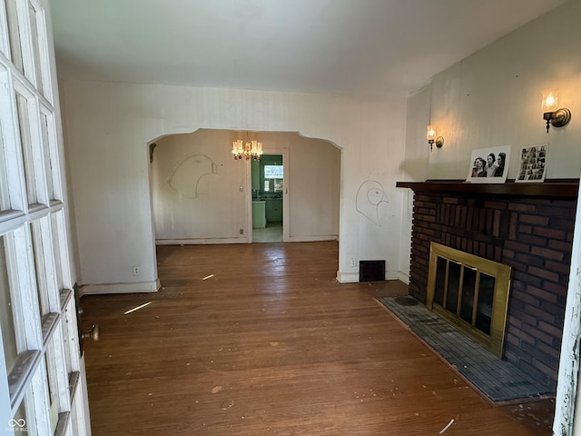 living area featuring baseboards, a chandelier, a fireplace, wood finished floors, and arched walkways