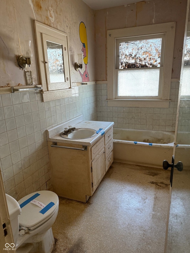 bathroom with vanity, wainscoting, tile walls, toilet, and a washtub