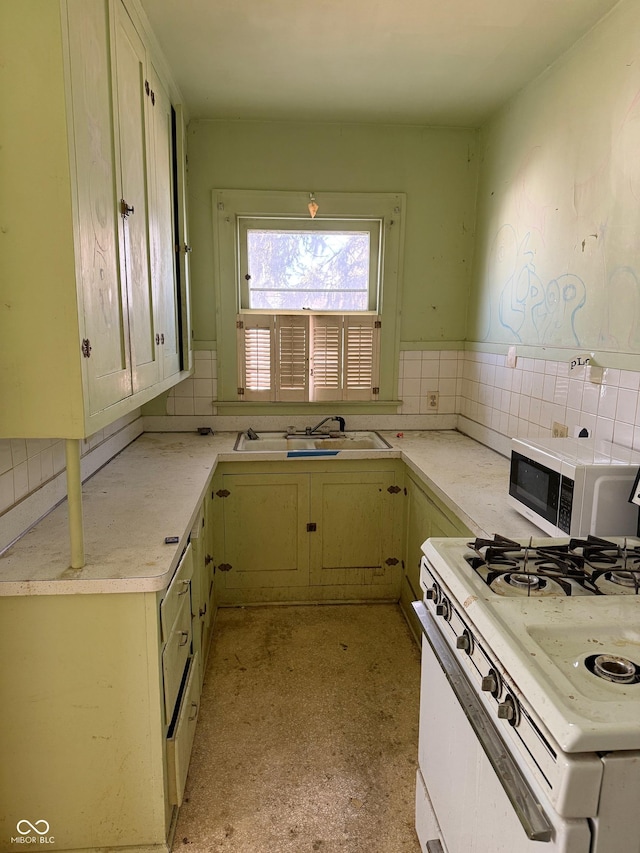 kitchen with a sink, white appliances, backsplash, and light countertops