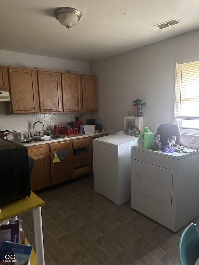 clothes washing area featuring laundry area, washing machine and dryer, visible vents, and a sink