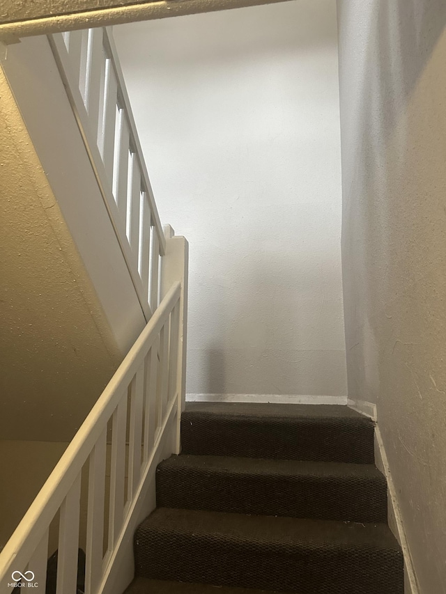 stairway with baseboards and a textured wall