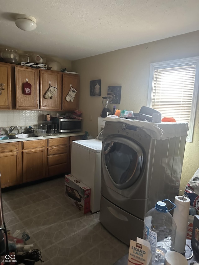 clothes washing area with a sink, a textured ceiling, washing machine and dryer, and laundry area