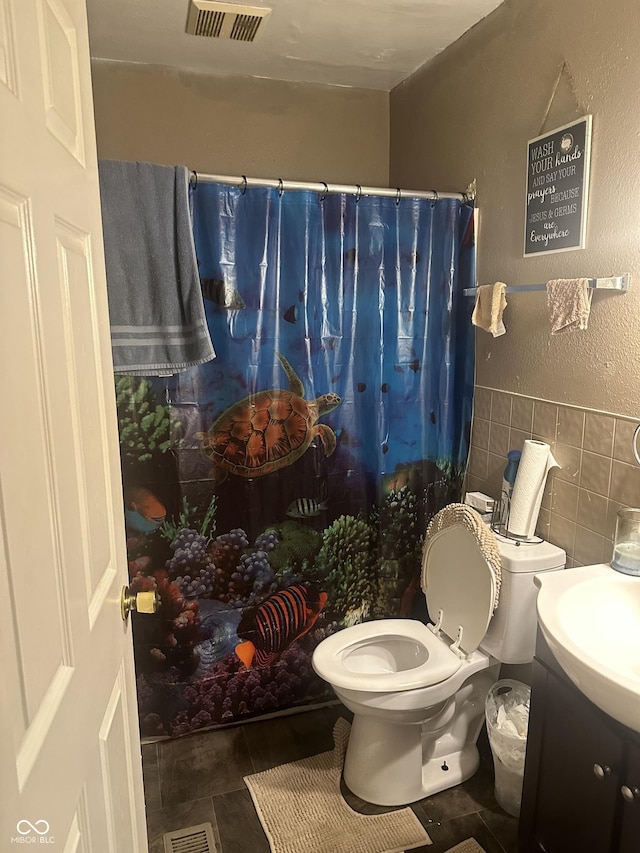 full bath featuring a shower with shower curtain, tile walls, toilet, and visible vents