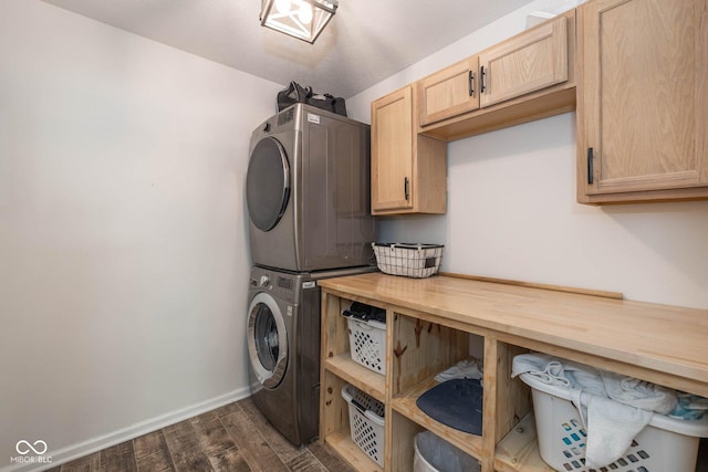 washroom featuring dark wood finished floors, cabinet space, stacked washer and clothes dryer, and baseboards