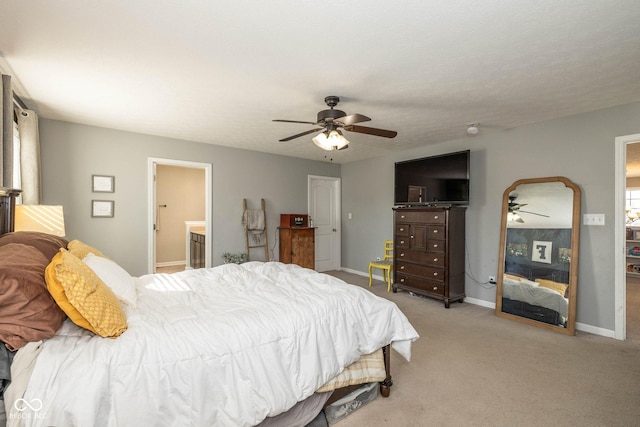 carpeted bedroom featuring baseboards, ensuite bathroom, and a ceiling fan