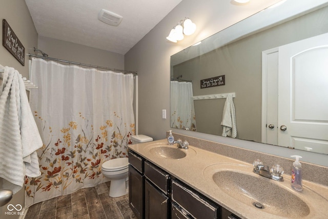 bathroom featuring a sink, toilet, double vanity, and wood tiled floor