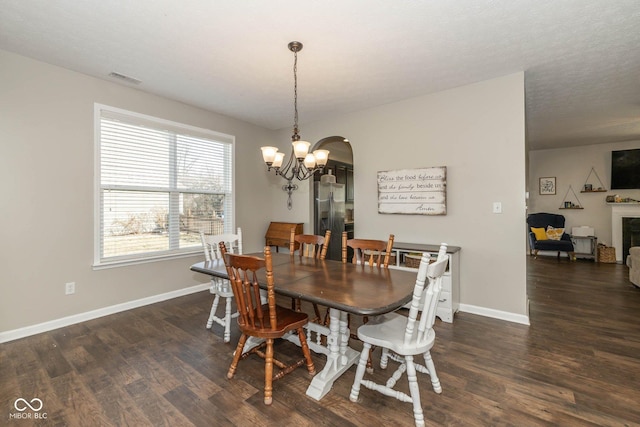 dining room featuring visible vents, baseboards, a chandelier, wood finished floors, and arched walkways