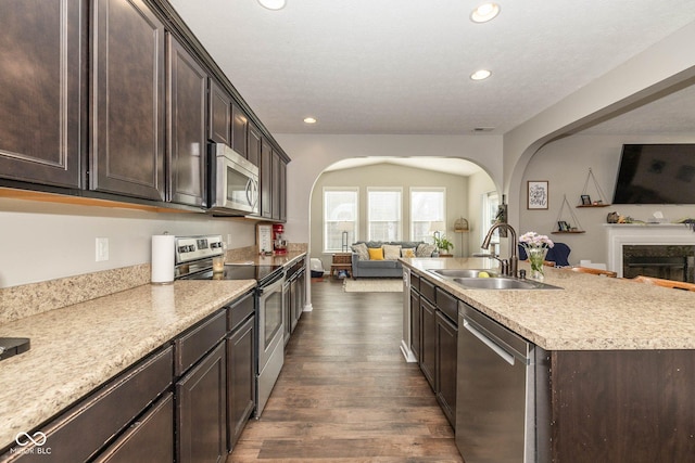 kitchen with arched walkways, open floor plan, appliances with stainless steel finishes, and a sink