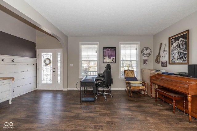 office area with arched walkways, baseboards, and dark wood-style flooring