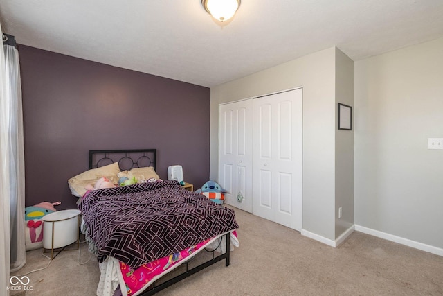 carpeted bedroom with a closet and baseboards