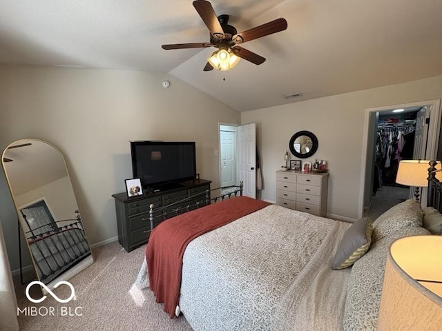 bedroom with a walk in closet, baseboards, light colored carpet, vaulted ceiling, and a ceiling fan