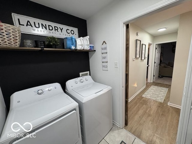 washroom featuring washer and dryer, baseboards, laundry area, and light wood finished floors