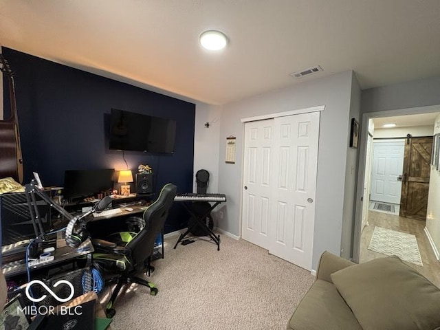 carpeted office featuring visible vents, a barn door, and baseboards