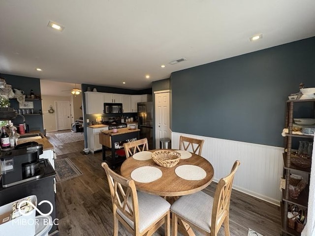 dining area with visible vents, dark wood-type flooring, a ceiling fan, recessed lighting, and wainscoting