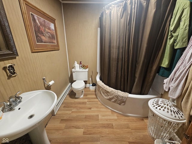 full bath featuring wood finished floors, a baseboard radiator, a sink, shower / bath combination with curtain, and toilet