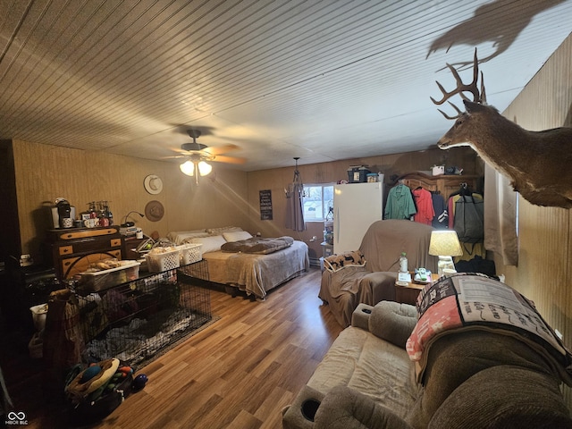 bedroom featuring wood finished floors, a ceiling fan, and wood walls