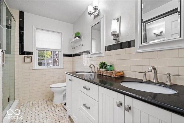 bathroom with a sink, tiled shower, toilet, and tile walls