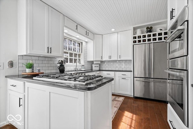 kitchen with a sink, appliances with stainless steel finishes, white cabinetry, and dark wood-style flooring