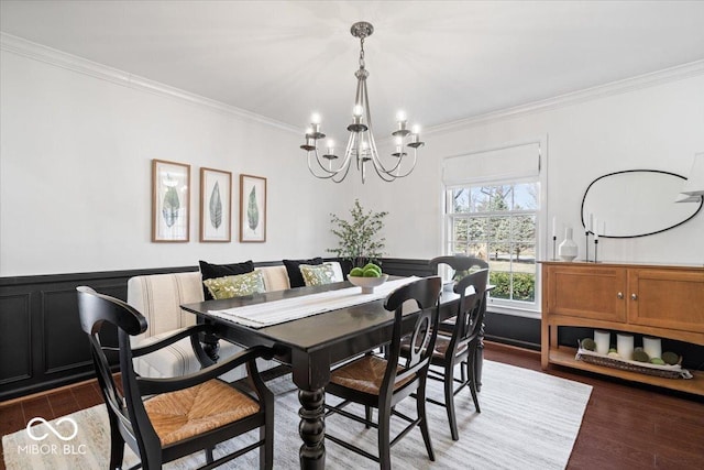 dining room featuring crown molding, wood finished floors, wainscoting, and a chandelier