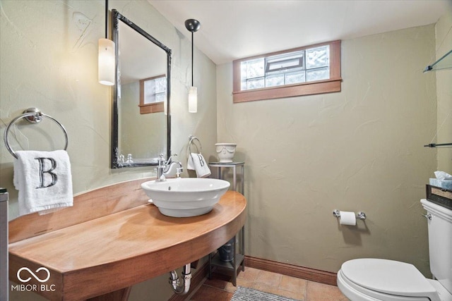 half bathroom with toilet, baseboards, and a sink