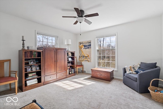 living area with a ceiling fan, baseboards, and carpet floors