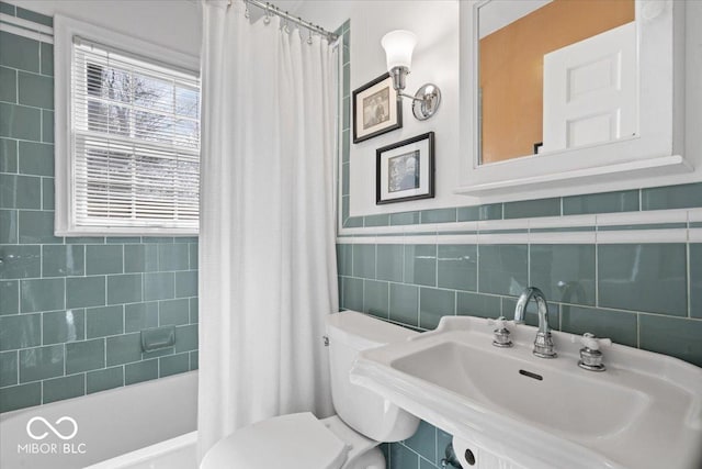 bathroom featuring shower / bath combo with shower curtain, toilet, tile walls, and a sink