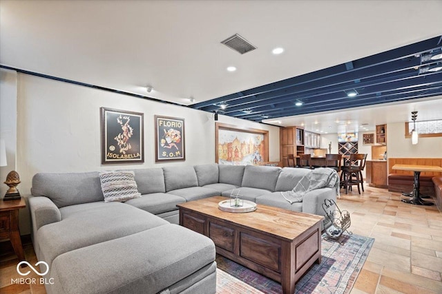 living room with recessed lighting, visible vents, stone tile floors, and beamed ceiling